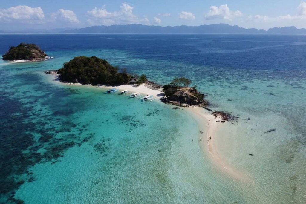 Vista aérea de una isla con banco de arena y barcos en Coron, Palawan, rodeada de aguas turquesas