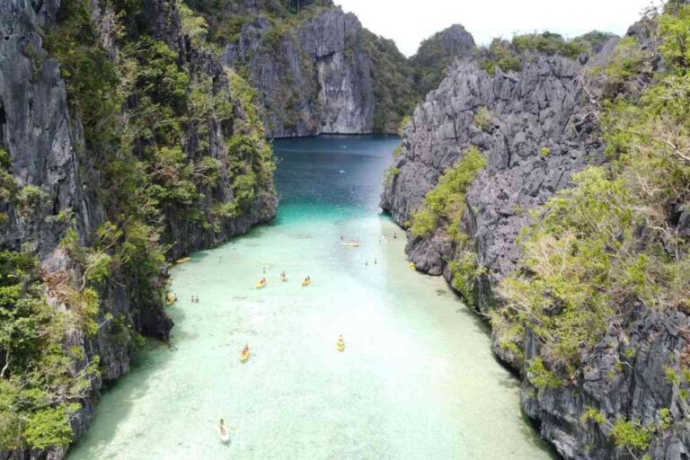 Vista aérea de la Big Lagoon en El Nido, Palawan, con kayakistas entre formaciones rocosas y aguas turquesas